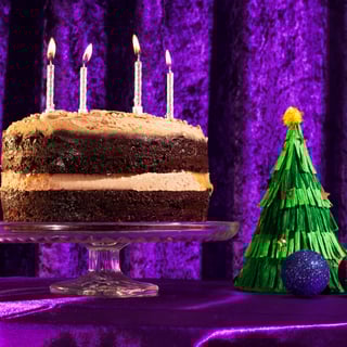 chocolate hazelnut cake with candles in with purple velvet backdrop and a small christmas tree