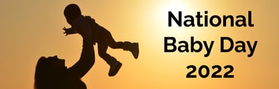 National Baby Day 2022 - Silhouette of woman holding a baby in the air, sunset background - Blog Banner