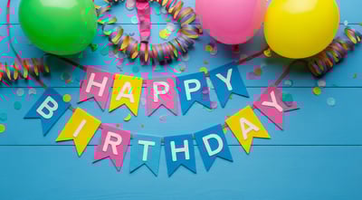 Happy birthday banner with ribbons and balloons on a blue background