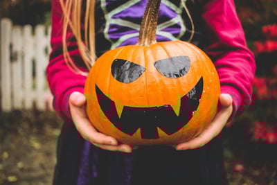 Child in fancy dress holding a pumpkin