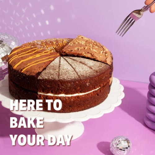 a sharing cake on a purple background with forks going in and the text 'here to bake your day' overlayed